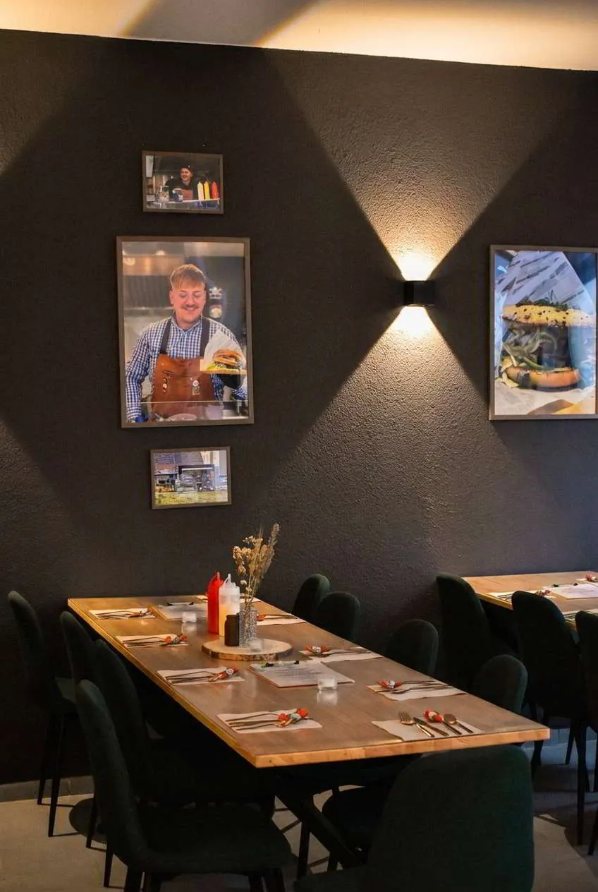 Innenraum der Blackbird Location mit Bar, Holztischen und dunklen Wänden.